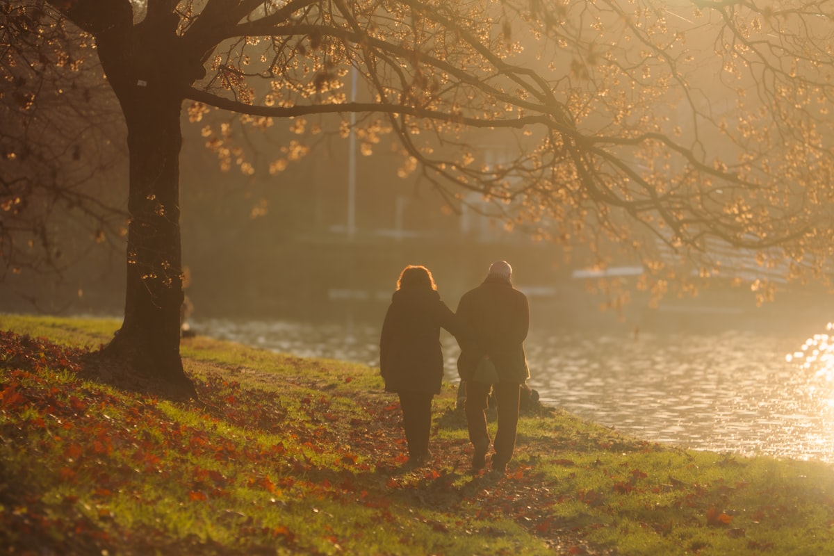 Paar spaziert im Herbstlicht am Fluss
