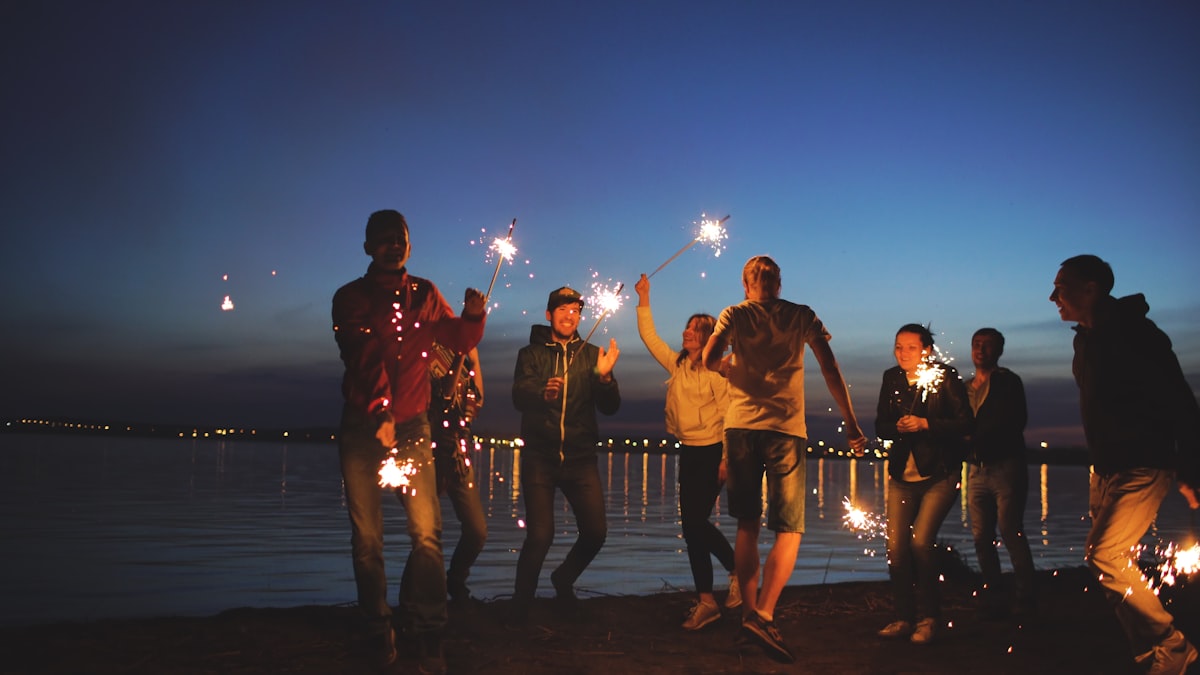 Freunde feiern abends mit Wunderkerzen am See